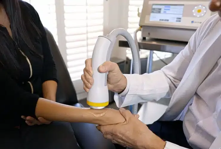 Clinician applying an acoustic wave therapy device to a patient's forearm