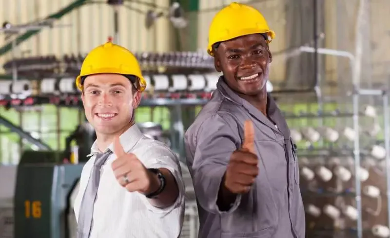 Two industrial workers wearing hard hats and safety gear